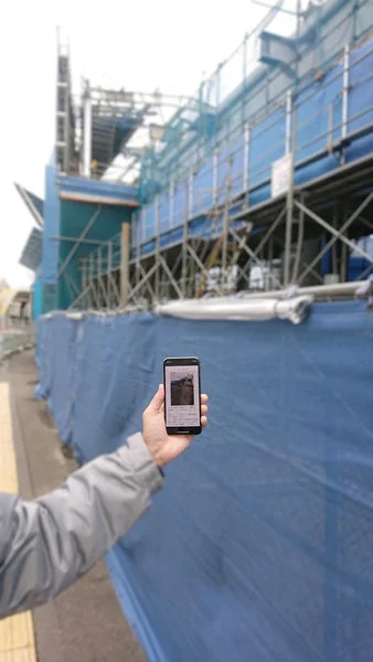 建設現場でスマートフォンを持つ人物
