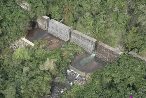 緑豊かな森林地帯に位置するコンクリート製のダムまたは堰を上空から捉えた画像