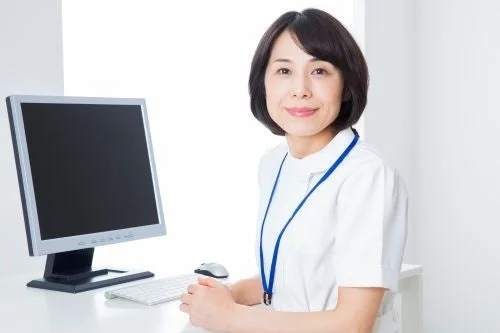 パソコンのあるデスクで笑顔の医療従事者