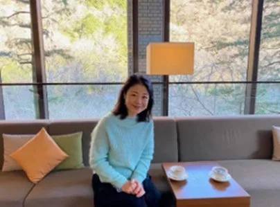 室内でソファに座り、笑顔を見せる女性の画像