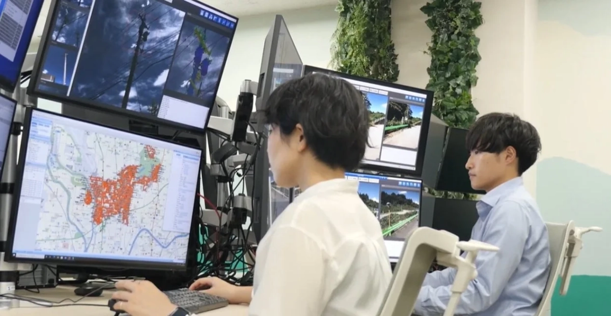 オフィスで2人の人物が複数のモニターを操作している様子