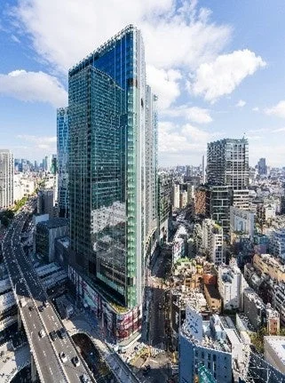 晴れた日の都市全景。ガラス張りの高層ビルがそびえ立ち、車が走る幹線道路が隣接