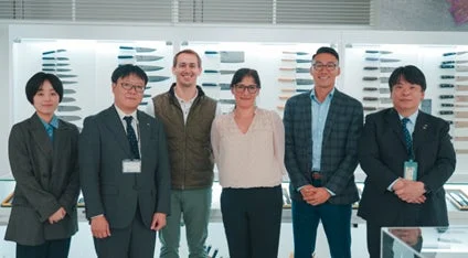 男女6人が笑顔で並び、背景には商品が展示されたショールームのような空間が広がる集合写真