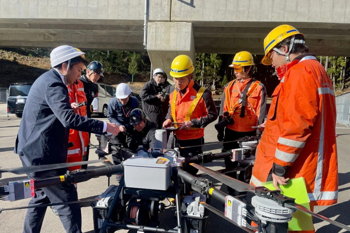 複数の作業員や技術者が屋外で大型ドローンを囲み、その操作や点検を行っています。