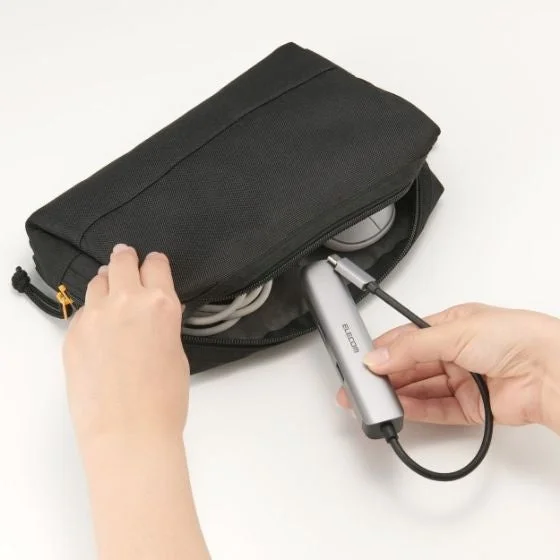 黒いガジェットポーチに、シルバーのUSBハブと複数のケーブル、マウスなどの電子機器アクセサリーを収納している様子