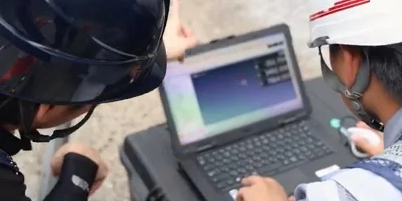 ノートパソコンの画面を共同で確認する作業員