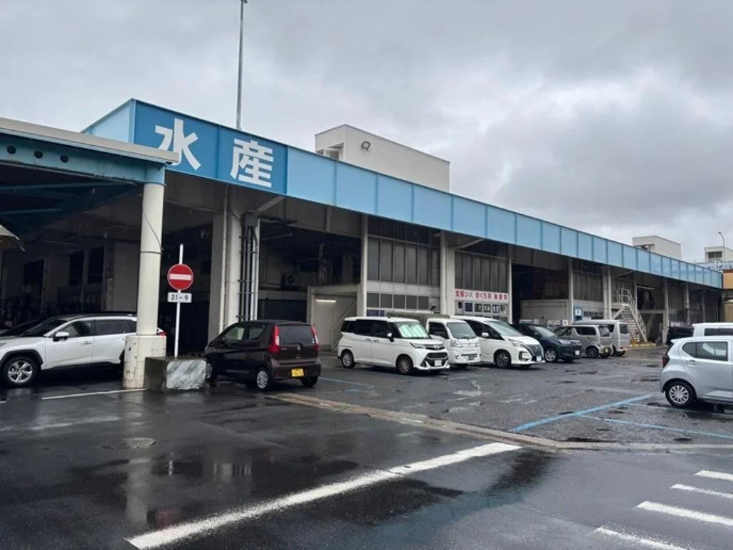 曇り空の下、多くの車が駐車している水産関連施設の様子を捉えた画像