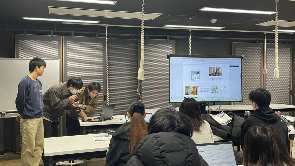 教室でモニターを見ながら学習や議論を行う学生たち