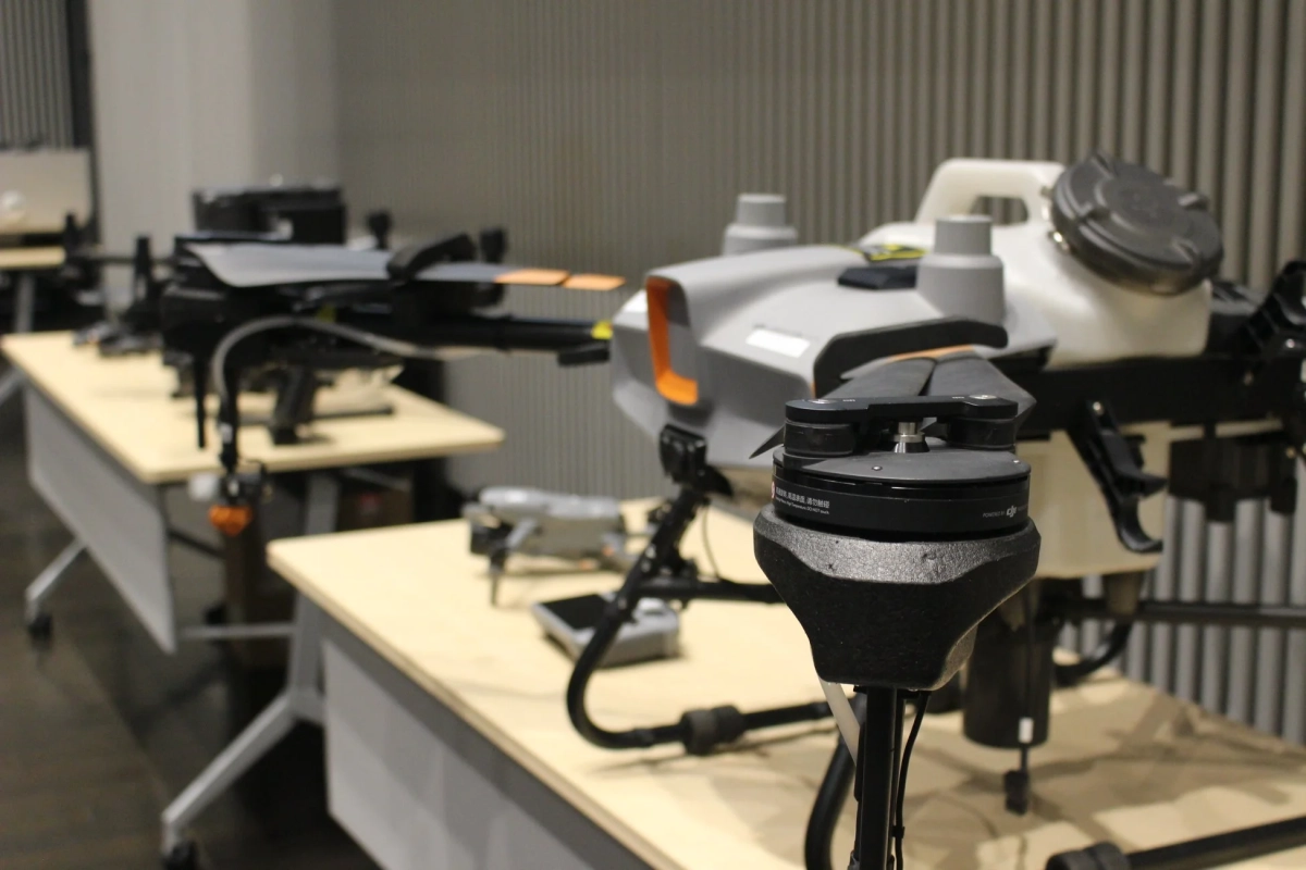 屋内の展示スペースで、複数のドローンがテーブルに並べられている
