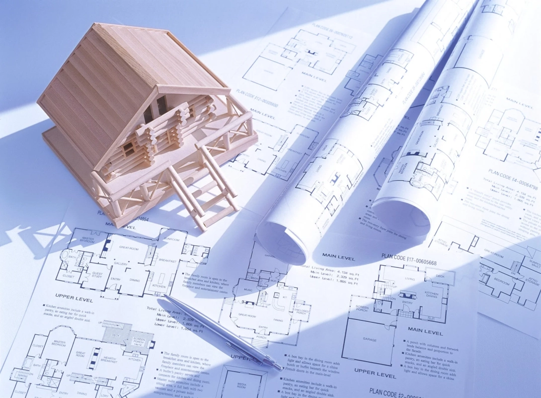 木製のログハウス風建築模型と複数の住宅設計図