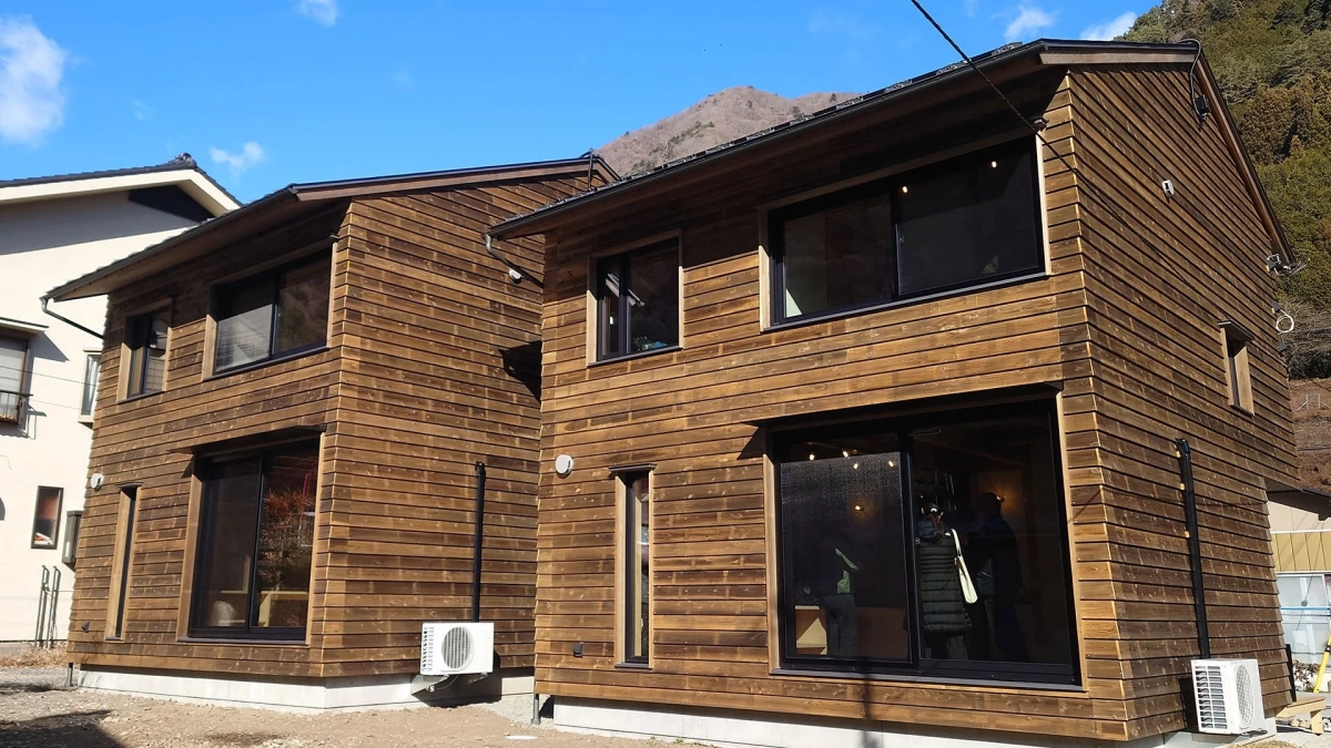 山を背景に木材の外壁が特徴的なモダンなデザインの住宅