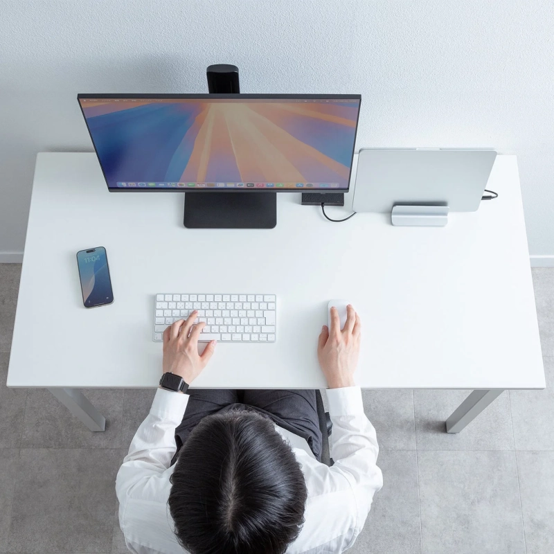 白いデスクでPC作業をするビジネスパーソンの俯瞰画像