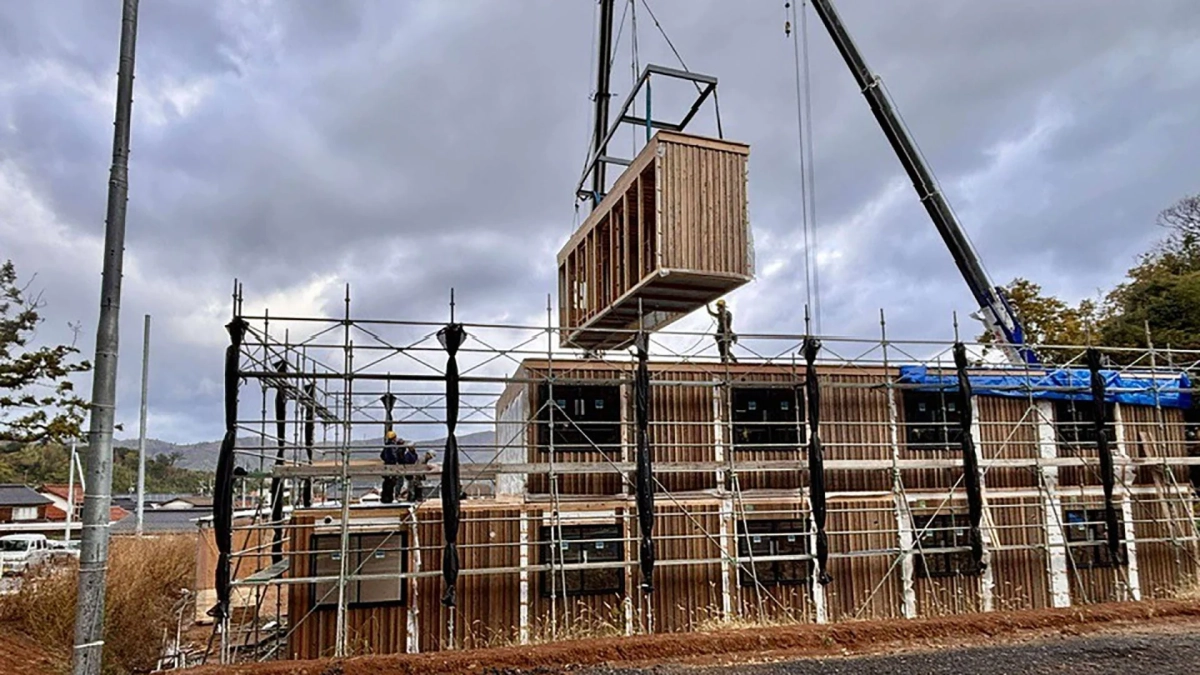 クレーンが木製のモジュール式ユニットを建設中の建物に設置している様子