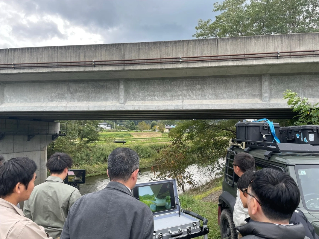 橋の下で人々がモニターを見ている風景