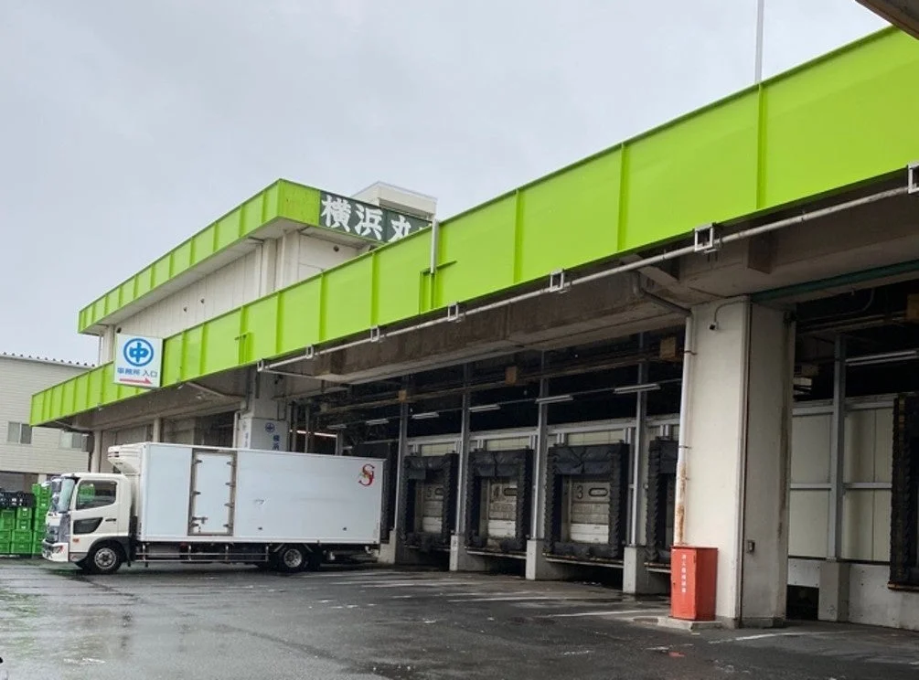 「横浜丸」と書かれた緑色の建物と複数の荷積みドックが写っている画像