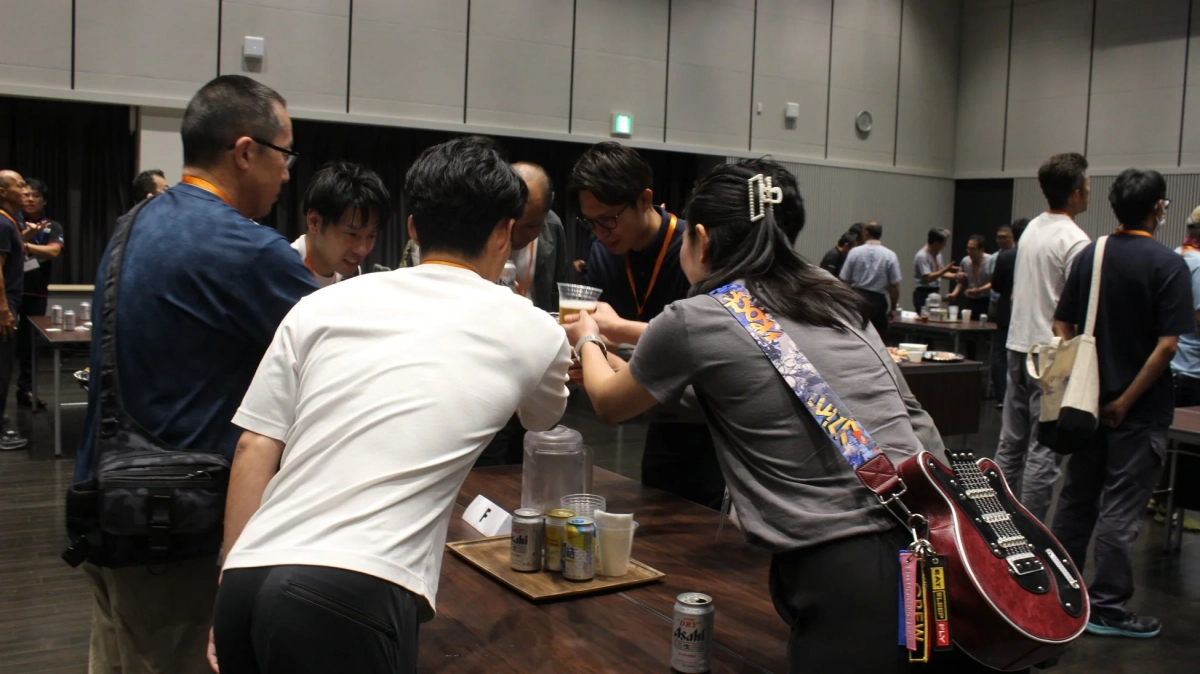 屋内の会場で人々が談笑し、飲み物を楽しんでいる交流会の様子