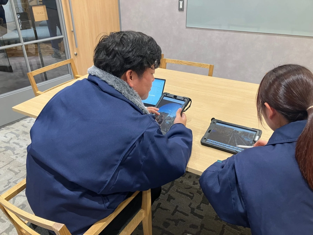 会議室でタブレットやラップトップを使う人物