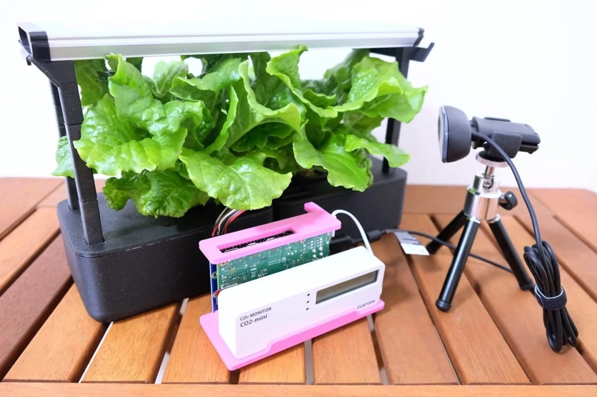 水耕栽培システムで育つレタスと、CO2モニター、カメラが写っています。