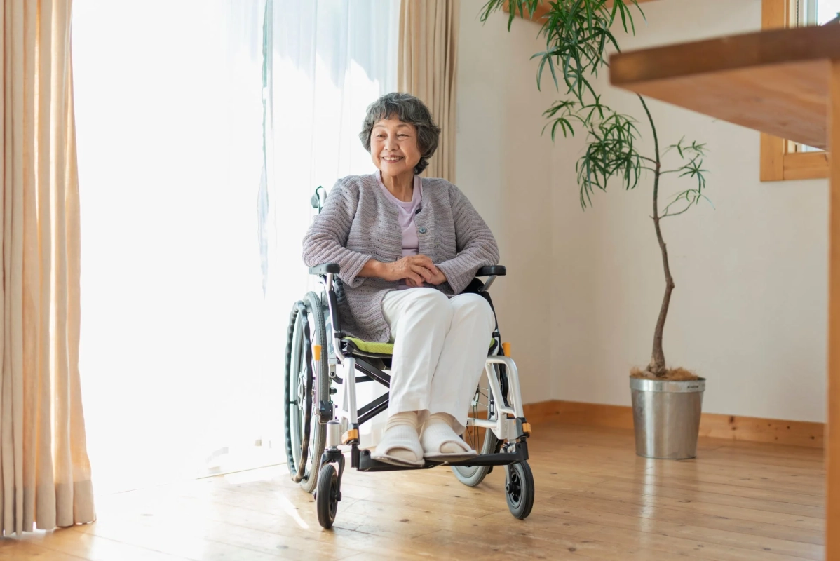 室内で車椅子に座り、穏やかに微笑む高齢の女性の様子