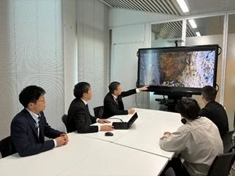 会議室で大型スクリーンを囲んで議論するビジネスパーソン