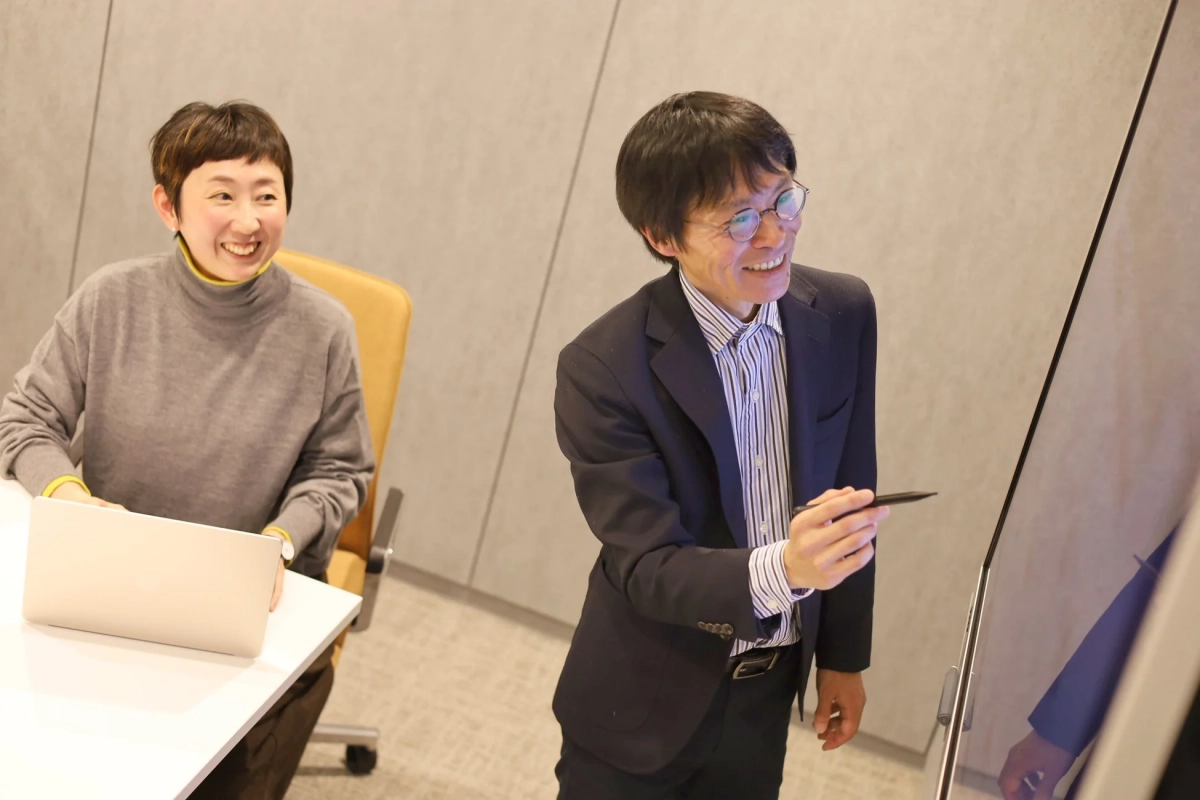 男性がデジタルホワイトボードを指しながらプレゼンしている