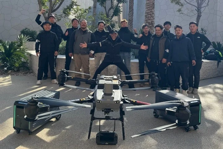 ドローンと電源装置を囲むプロジェクト関係者