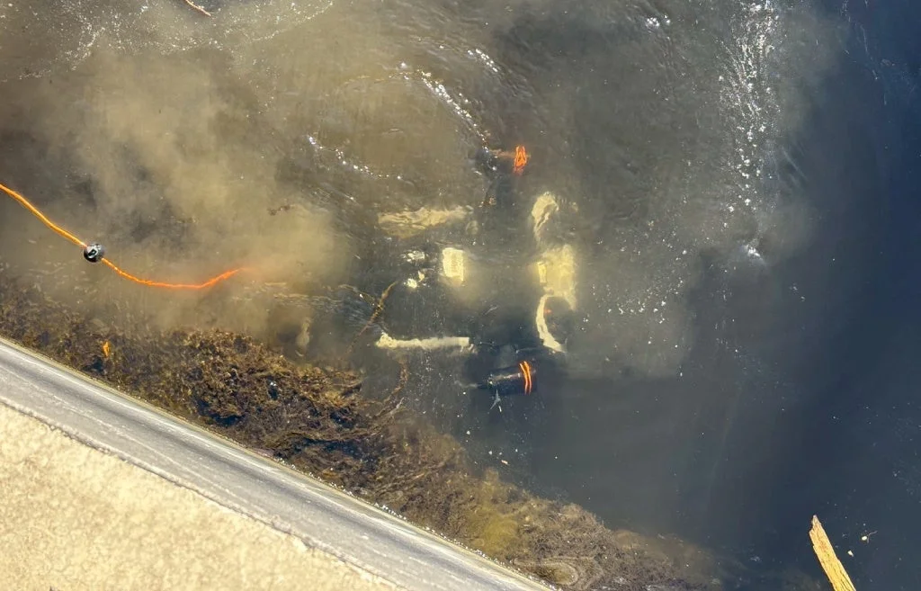 濁った水中に沈んだ車両が写っており、オレンジ色のロープが見える