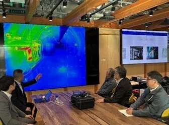 会議室でサーモグラフィー画像を見ながら議論する男性たち