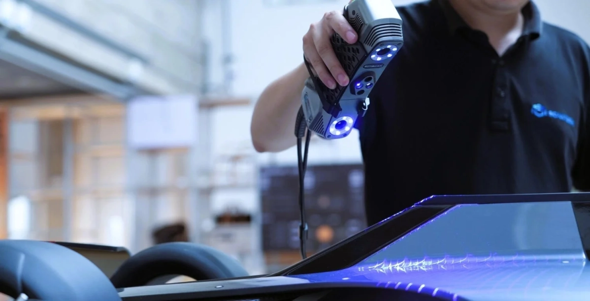 男性がハンディタイプの3Dスキャナーを使って、車両の一部を測定している様子