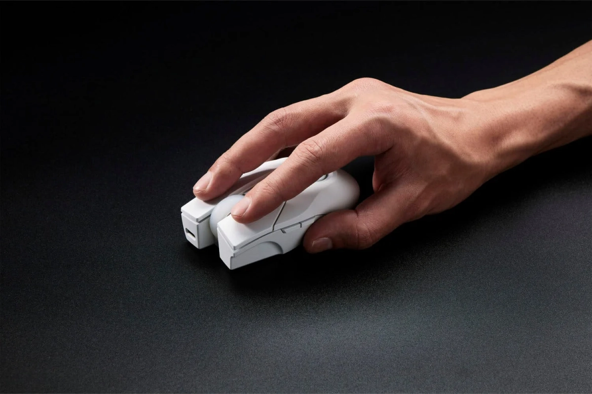 黒い背景のデスク上で、白いコンピューターマウスを操作する人物の手元がクローズアップされています。