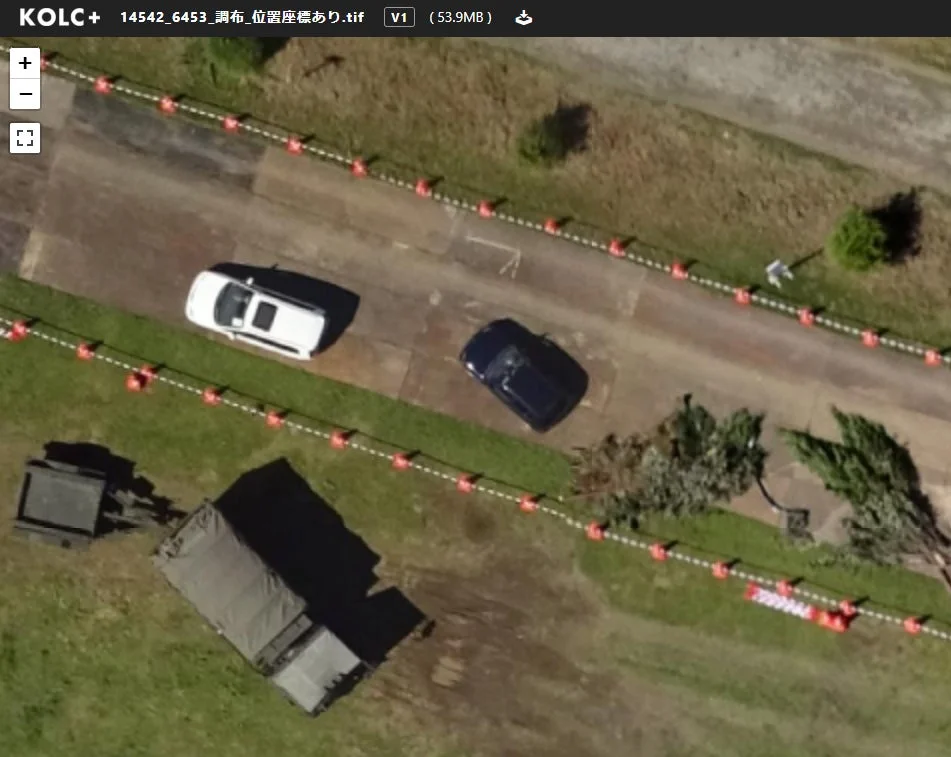 上空から撮影された三角コーンが並ぶ道と建物