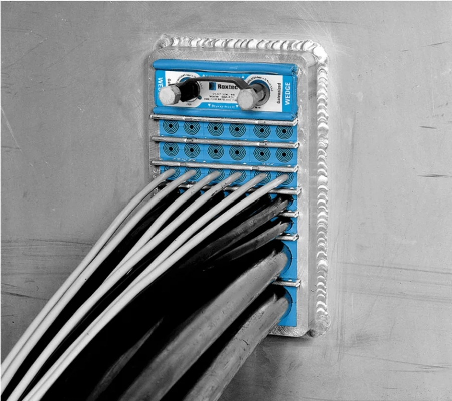 金属壁に溶接された青いケーブル貫通システムが写っています。