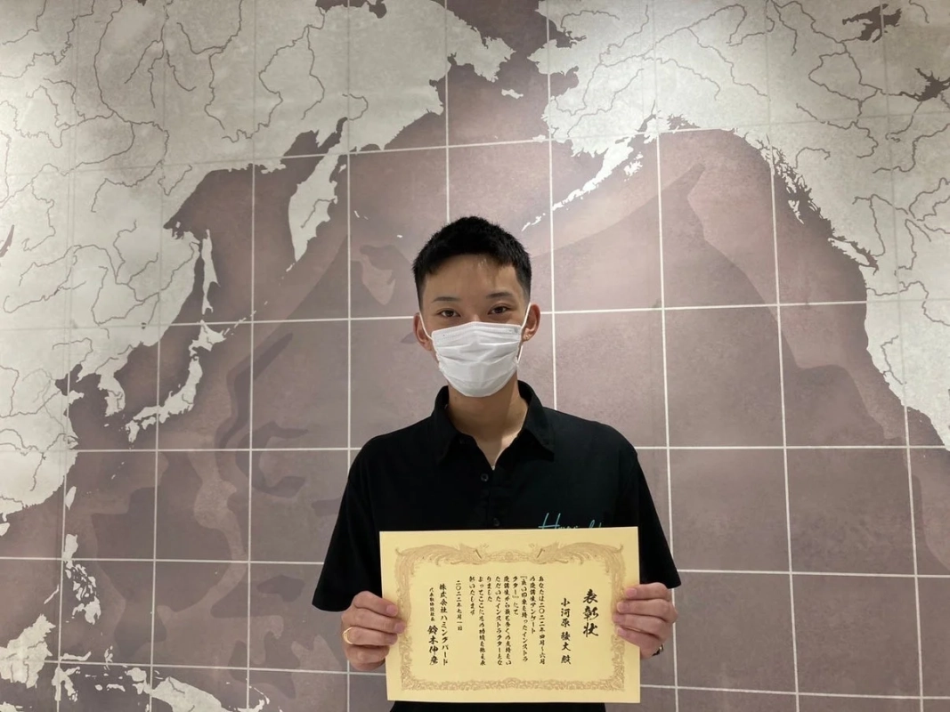 表彰状を手にマスクを着用した男性