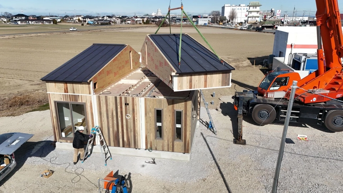 建設現場でクレーンが屋根を設置している様子