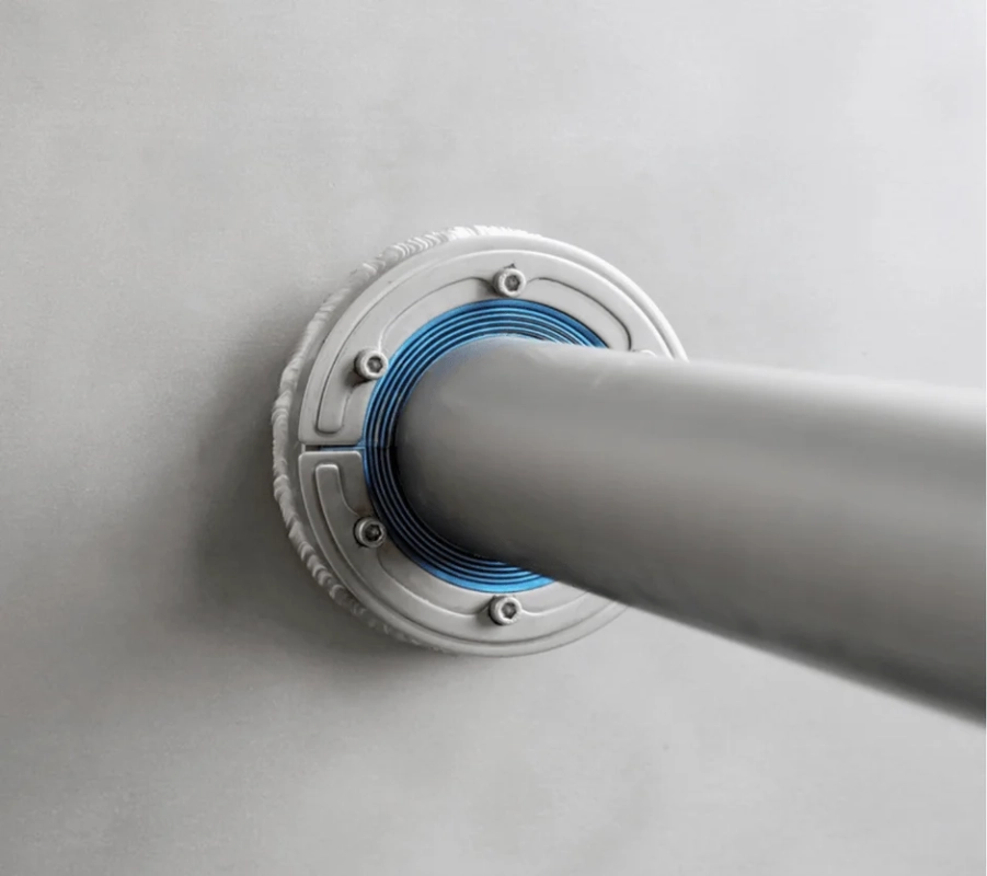 明るい灰色の壁から伸びる金属製のパイプの接合部をクローズアップした画像です。