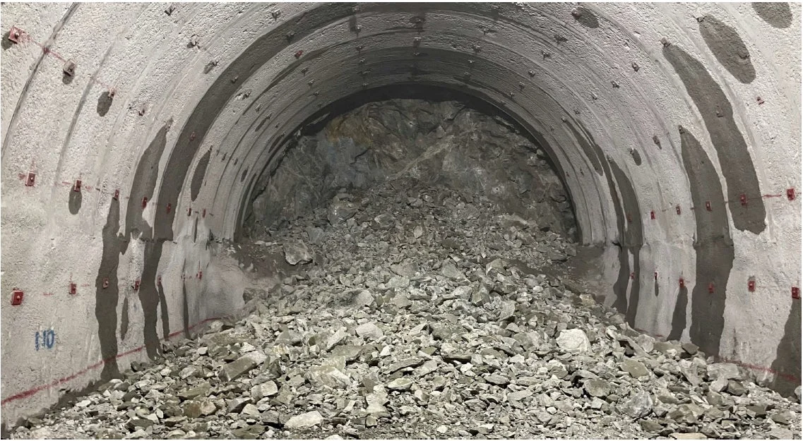 コンクリートで補強されたトンネルの奥が落盤により大量の岩石で塞がれており、壁には水漏れの跡が見られます。