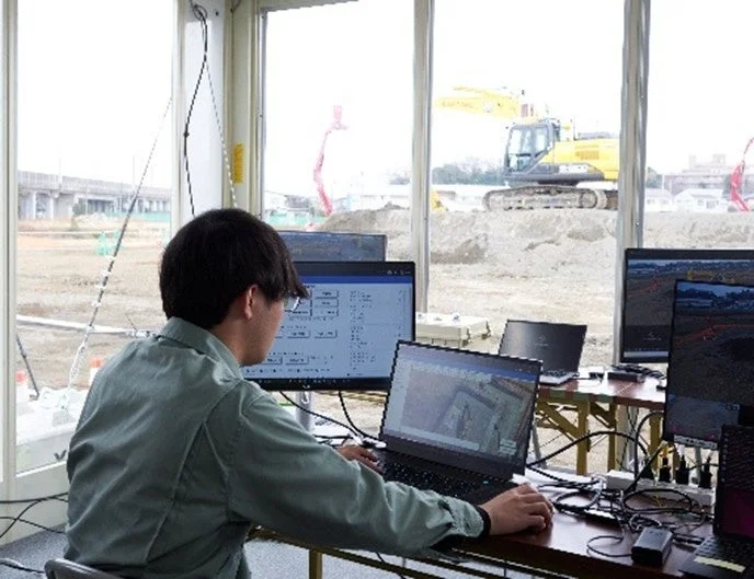 複数のモニターとノートパソコンを操作する作業員