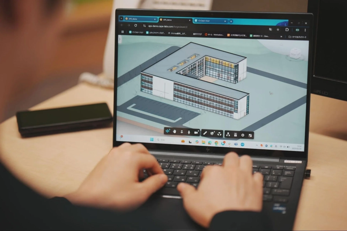ノートパソコンでU字型の建物の3D建築モデルが表示された画面を操作している様子