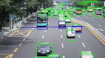 交通量の多い多車線道路の俯瞰図で、多数の車とバスが走行しており、車両には緑色の検出ボックス、一部には青い追跡線やボックスが重ねて表示