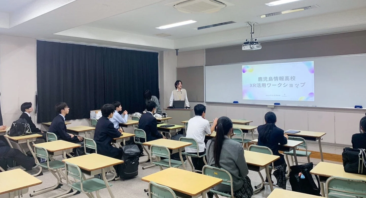鹿児島情報高校の教室でXR活用ワークショップが開催されている様子。講師が前に立ち、生徒たちが熱心に話を聞いている。