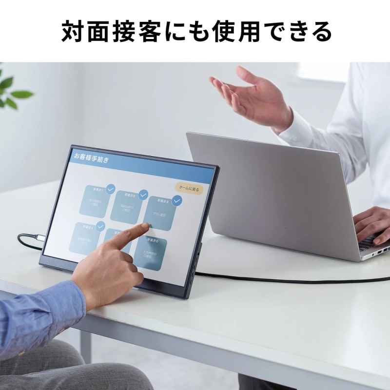 対面接客の場面で、顧客がポータブルモニターを操作して手続きを進めている様子