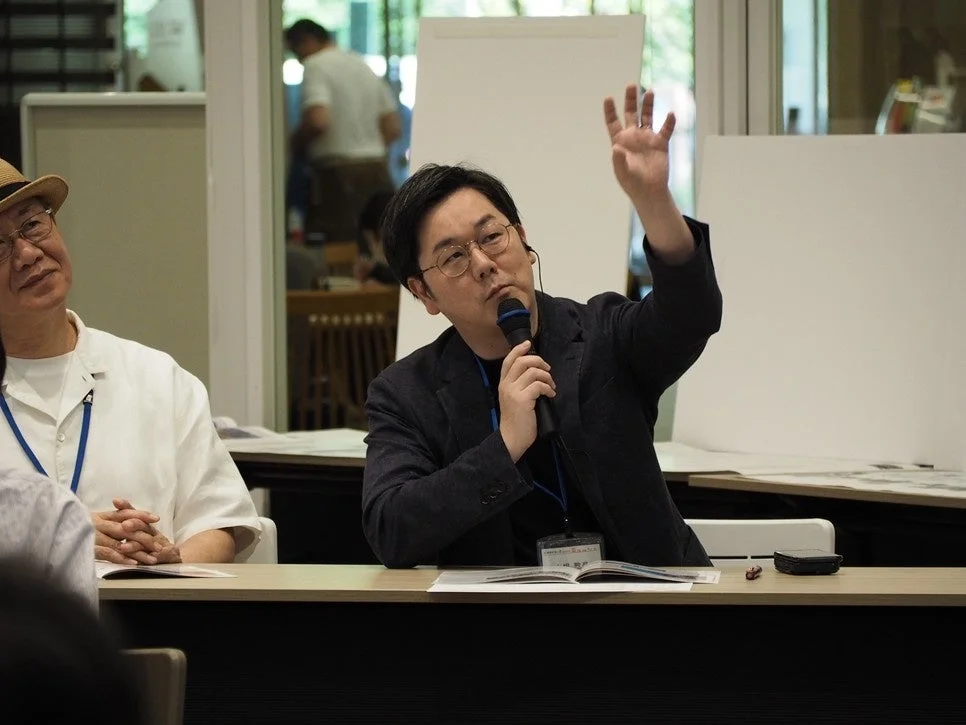 会議かセミナーで男性がマイクを持ち発言している様子
