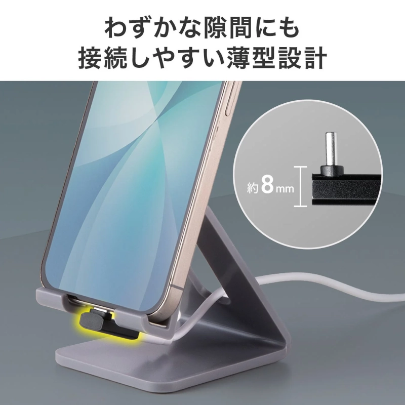 スマートフォンがスタンドに置かれ、充電ケーブルが接続されている様子です。わずかな隙間にも差し込みやすい約8mmの薄型設計のコネクタが特徴で、使いやすさをアピールしています。