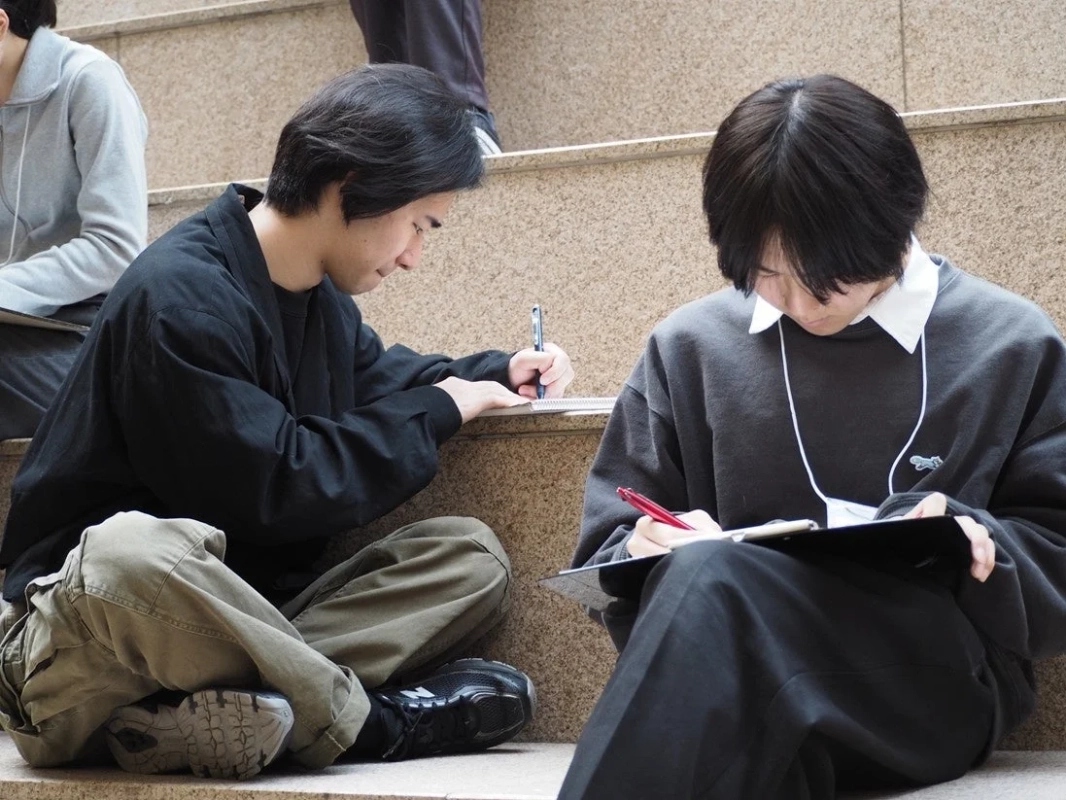 階段に座って書き物をしている若者たち