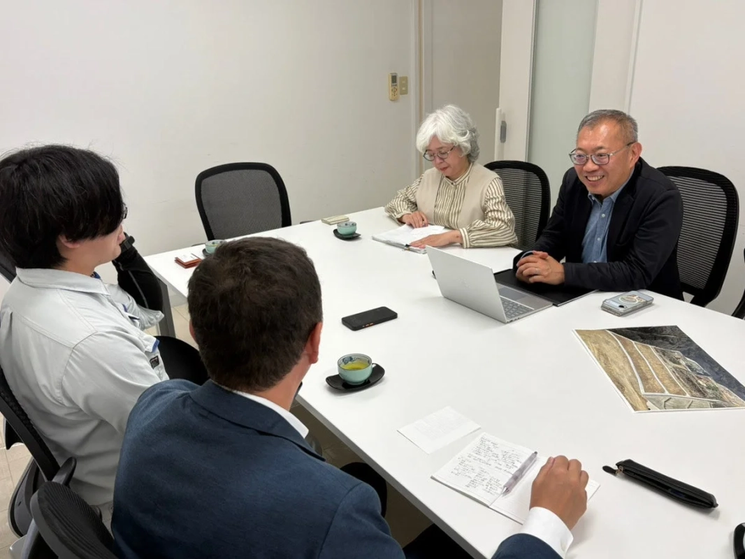 オフィスで4人が白いテーブルを囲んで会議をしている様子