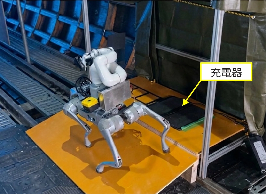 オレンジ色の台の上に立つ四足歩行ロボットと充電器