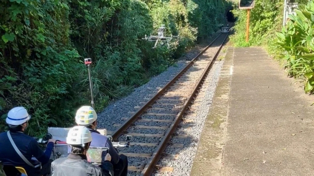 鉄道線路の近くでドローンを操作し点検作業を行う作業員たち