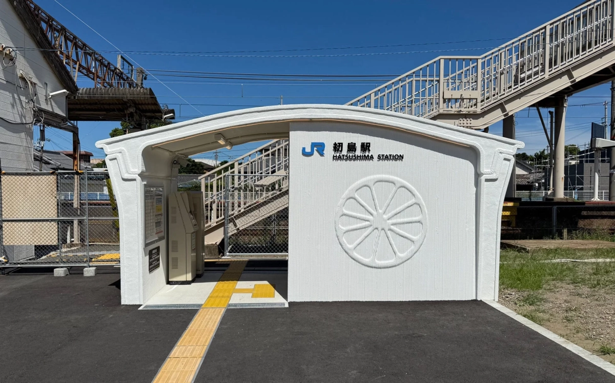 青空の下、白いモダンなデザインのJR初島駅の駅舎