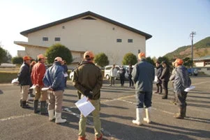 屋外で集まって説明を聞く人々