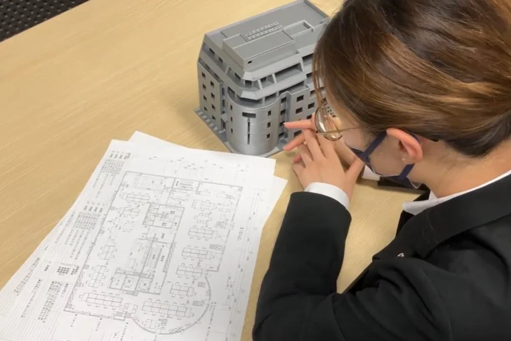 建物の模型と設計図を確認する女性